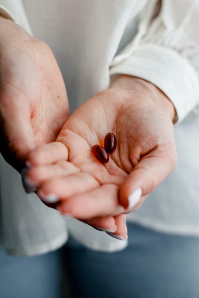 Two dietary supplement pills in a woman’s hands